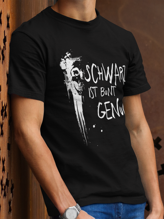 Junger Mann trägt ein schwarzes T-Shirt mit Graffiti-Schädel und dem Text „Schwarz ist bunt genug“, Oberkörperansicht