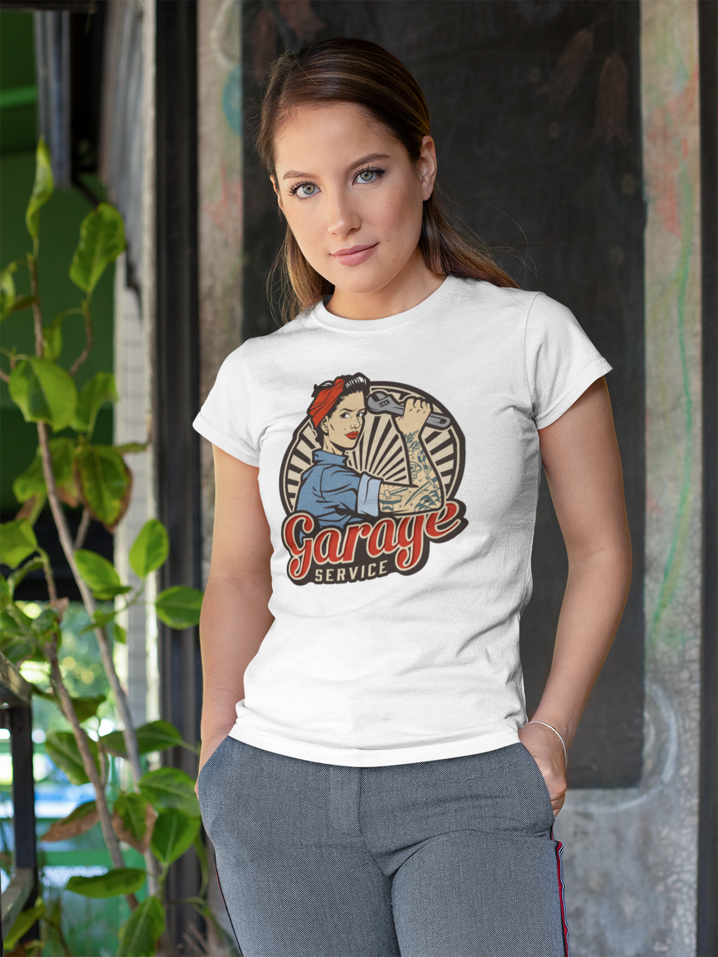 Junge Frau trägt ein weißes T-Shirt mit Rockabilly-Motiv einer starken Frau mit Werkzeug, Oberkörperansicht