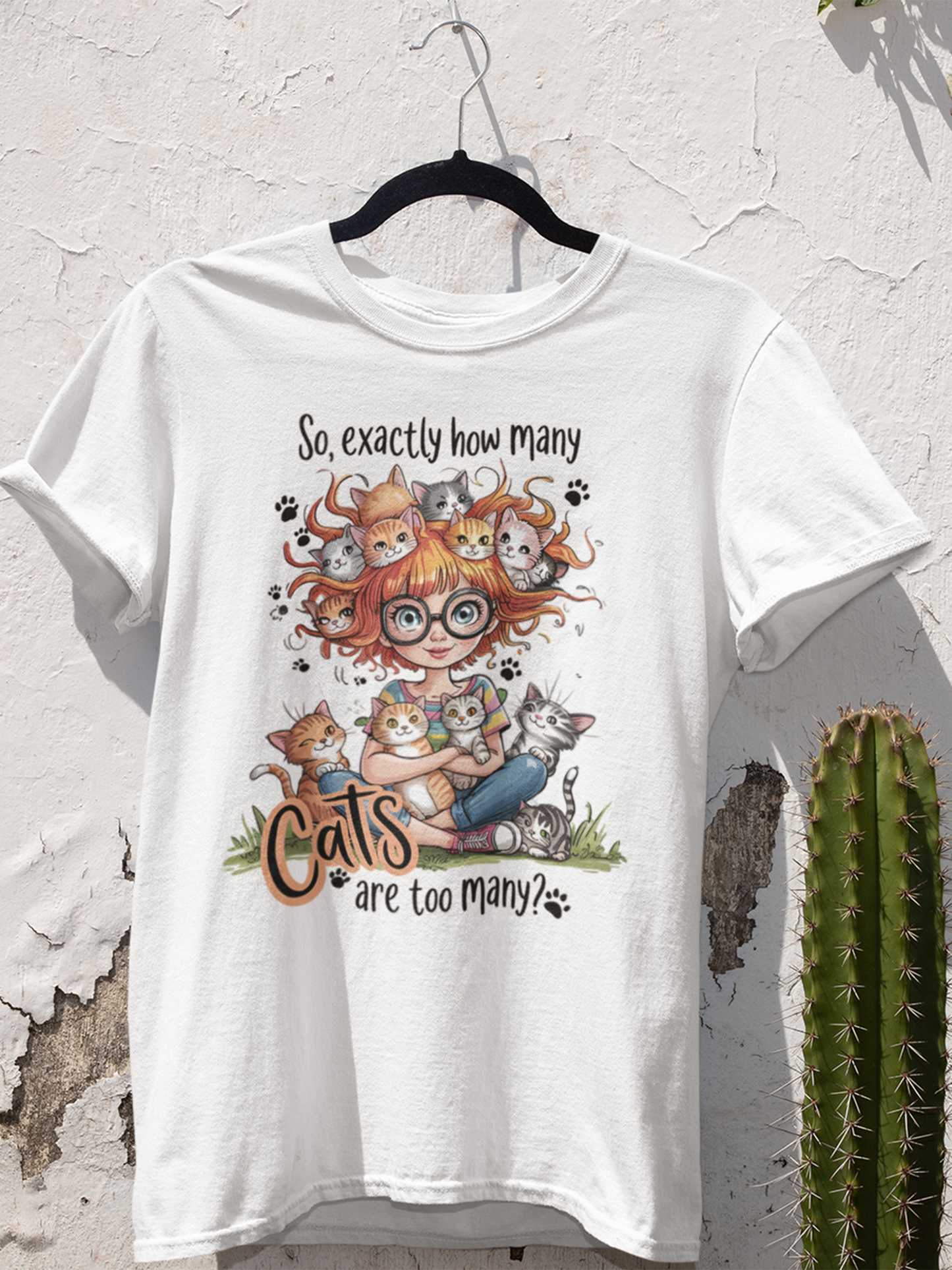 Damen T-Shirt auf Kleiderbügel mit Spruch „How many cats are too many?“ und süßem Motiv einer Katzenmama mit vielen Katzen – Weiß, leicht tailliert, Vorderansicht