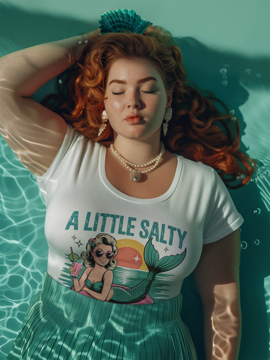 Frau mit rotem Haar im Wasser liegend, mit weißem -Shirt und Aufschrift "A little salty" und Meerjungfrau.
