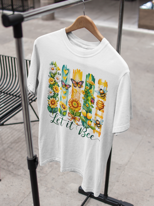 Weißes T-Shirt auf Holzkleiderbügel an Kleiderständer, mit gelben Blumen, mehreren Bienen und dem Schriftzug „Let it bee“.