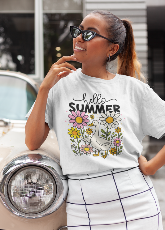 Frau lehnt lässig an einem Auto und trägt ein weißes T-Shirt mit Motiv: Gans im Blumenbeet und Schriftzug „Hello Summer“