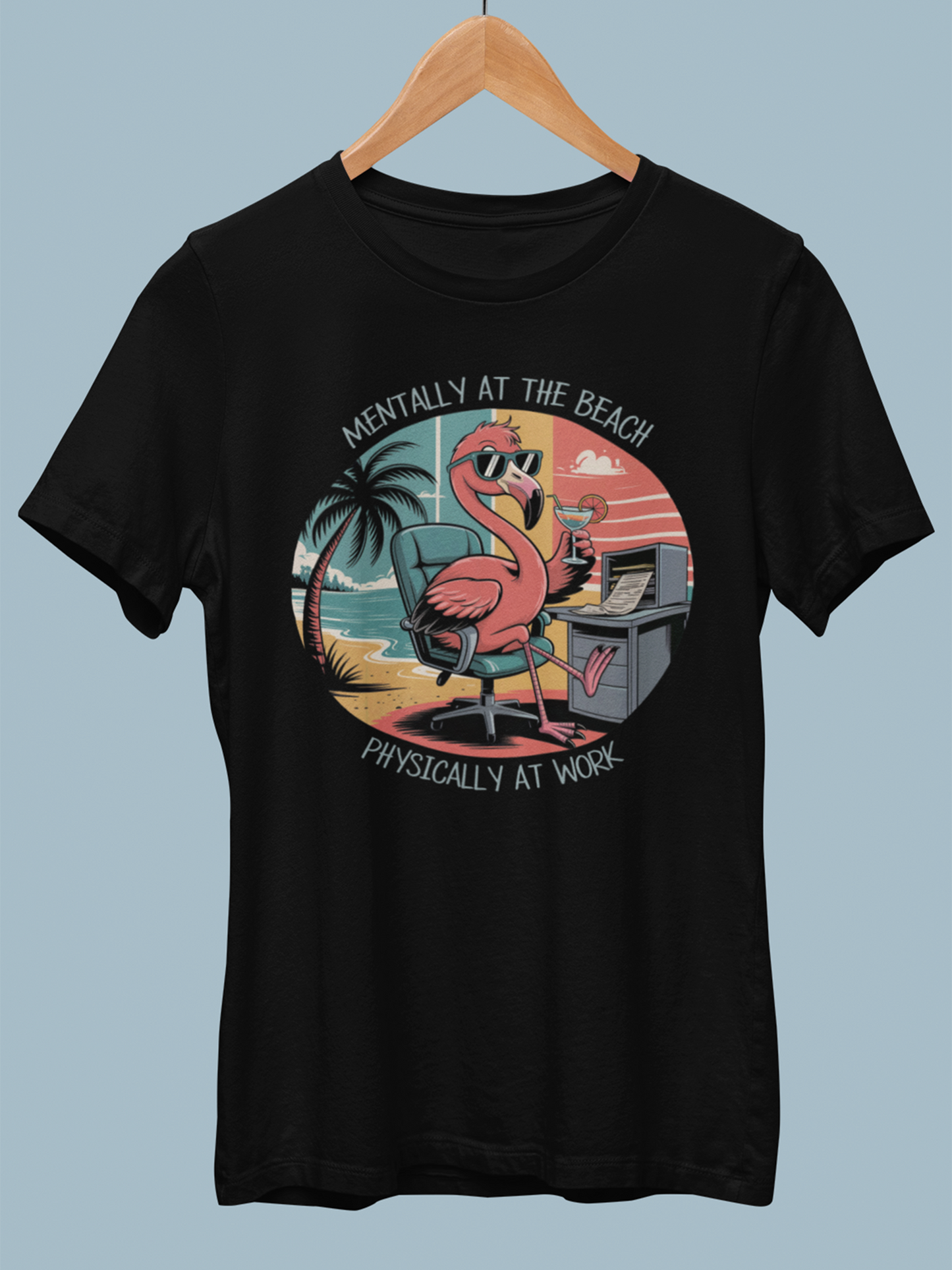 Schwarzes Shirt mit Flamingo-Motiv hängt auf Holzkleiderbügel.