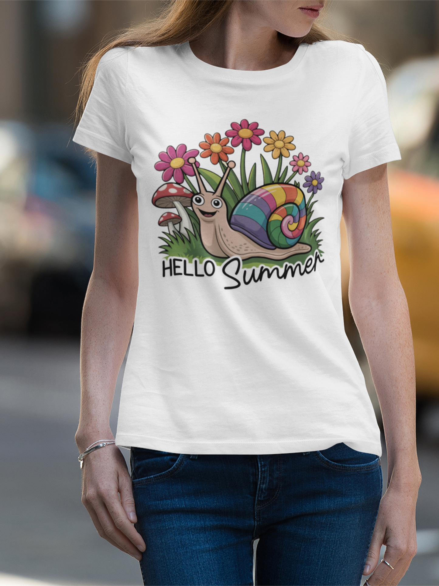Frau mit Kappe trägt ein weißes T-Shirt mit süßem Comic-Motiv: kleine Schnecke im Blumenbeet, umgeben von Blüten, Text „Hello Summer“. Das Bild zeigt nur den Oberkörper.
