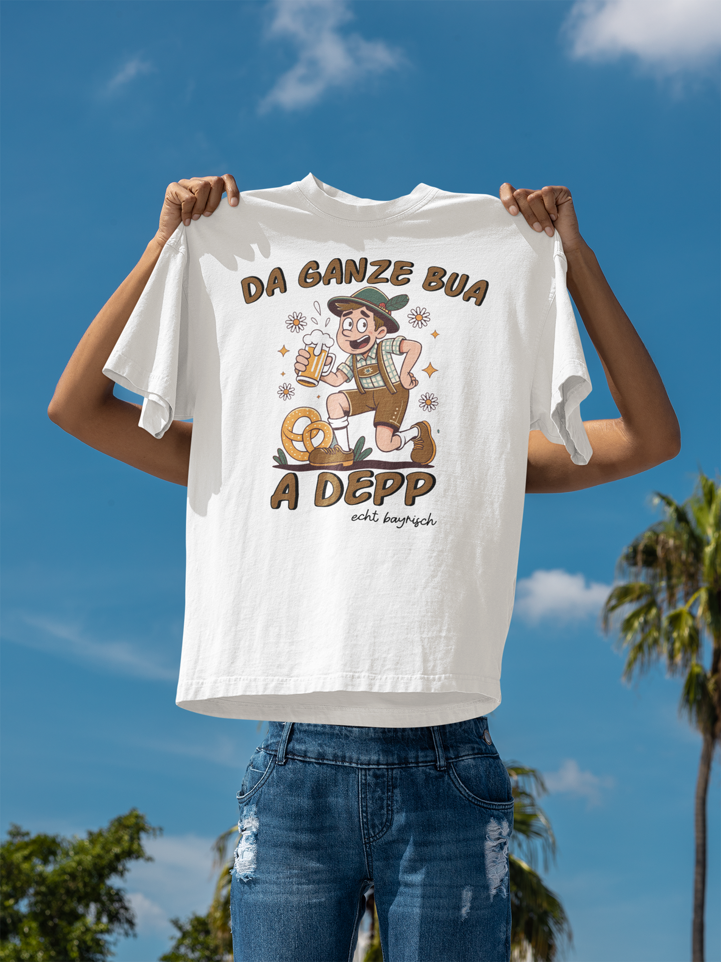 Weißes T-Shirt mit Motiv: bayerischer Mann mit Maßkrug und Spruch „Da ganze Bua a Depp“, es wird von zwei Armen in die Höhe gehalten