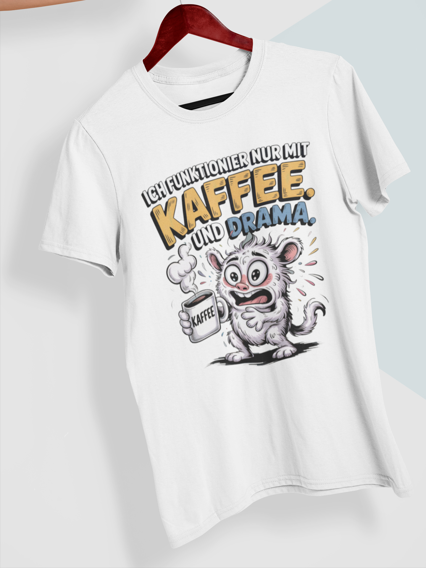 Weißes T-Shirt mit verrücktem Monster und dem Text „Ich funktionier nur mit Kaffee und Drama“ auf Kleiderbügel