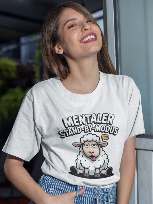 Lachende junge Frau trägt weißes T-Shirt mit müdem Schaf und Text „Mentaler Stand-By-Modus“ (Oberkörperaufnahme)