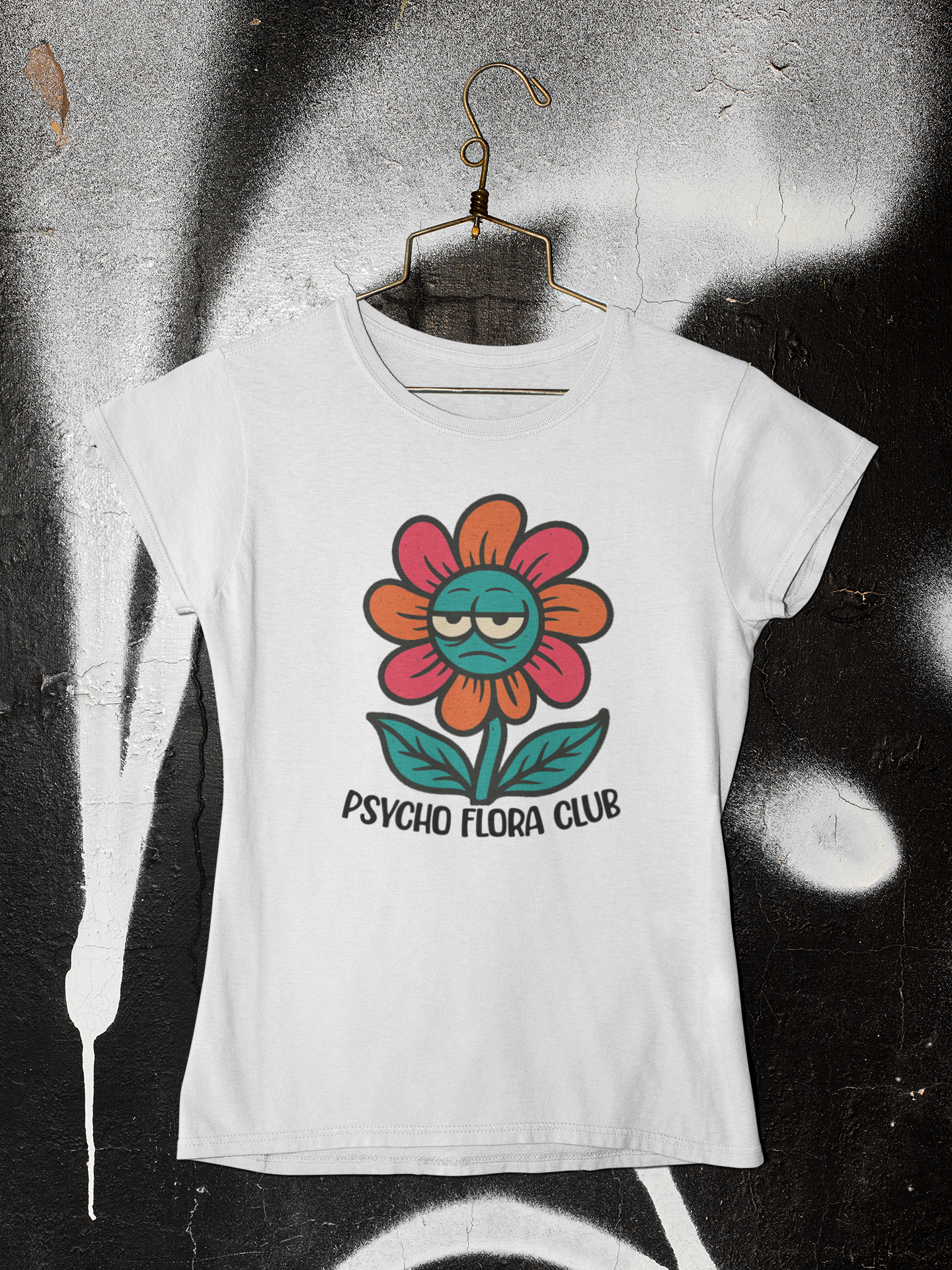 Weißes T-Shirt mit Retro-Blume mir Augen und Schriftzug „Psycho Flora Club“ auf Kleiderbügel an grau-schwarzer Wand.
