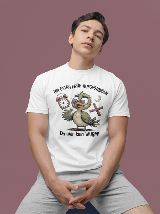 Jnger Mann, sitzend. Er trägt ein weißes T-Shirt mit Vogel-Motiv und Text „Bin extra früh aufgestanden – Da war kein Wurm“