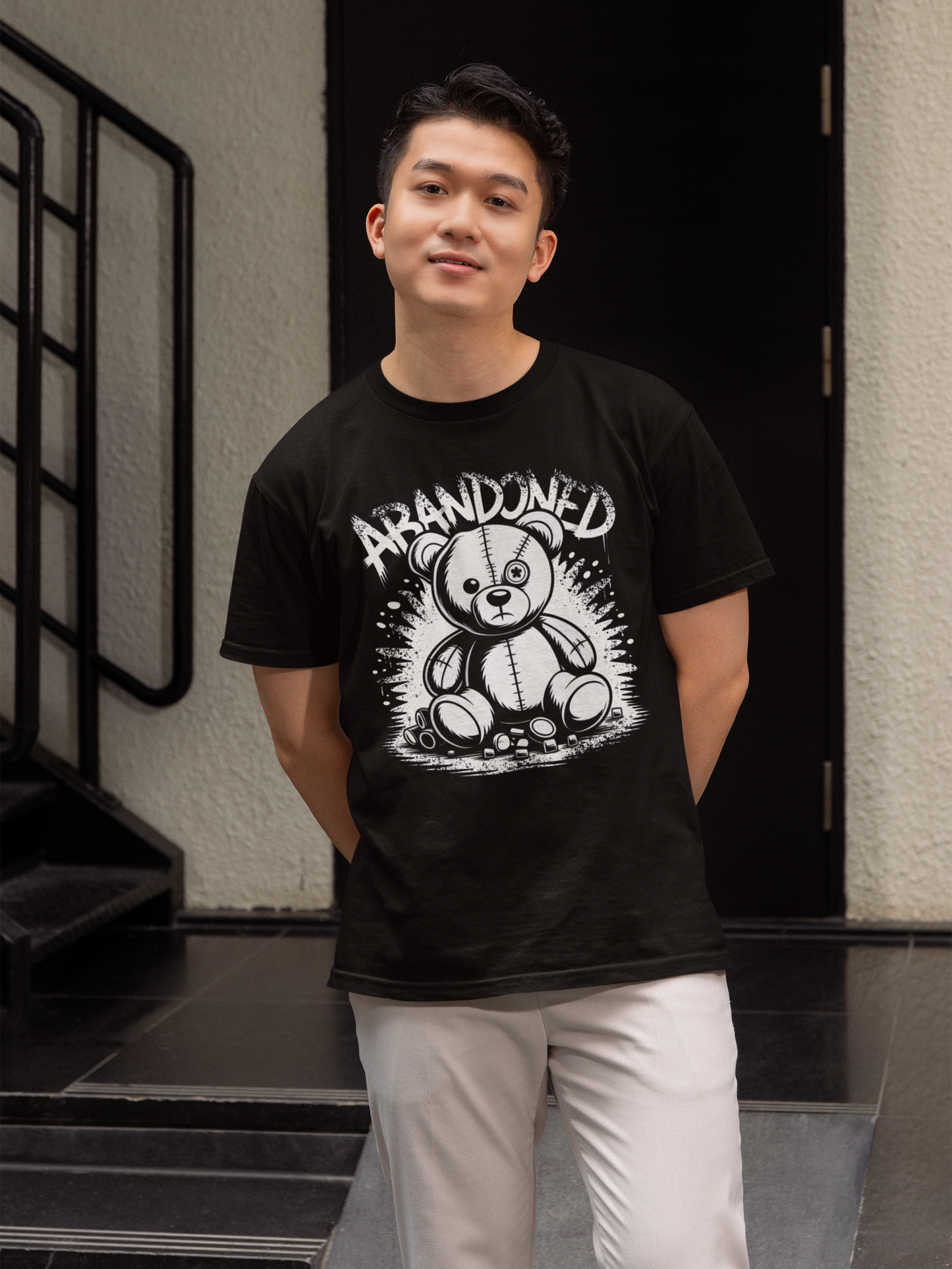 Junger Mann trägt schwarzes T-Shirt mit Abandoned Teddy Graffiti-Motiv (Oberkörperaufnahme)