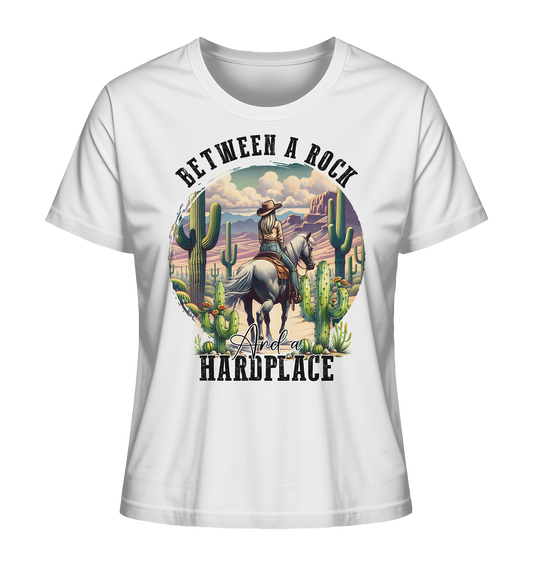 Weißes T-Shirt mit Cowgirl auf Pferd in der Wildniss mit Kakteen. Schriftzug: Between a rock and a heardplace.