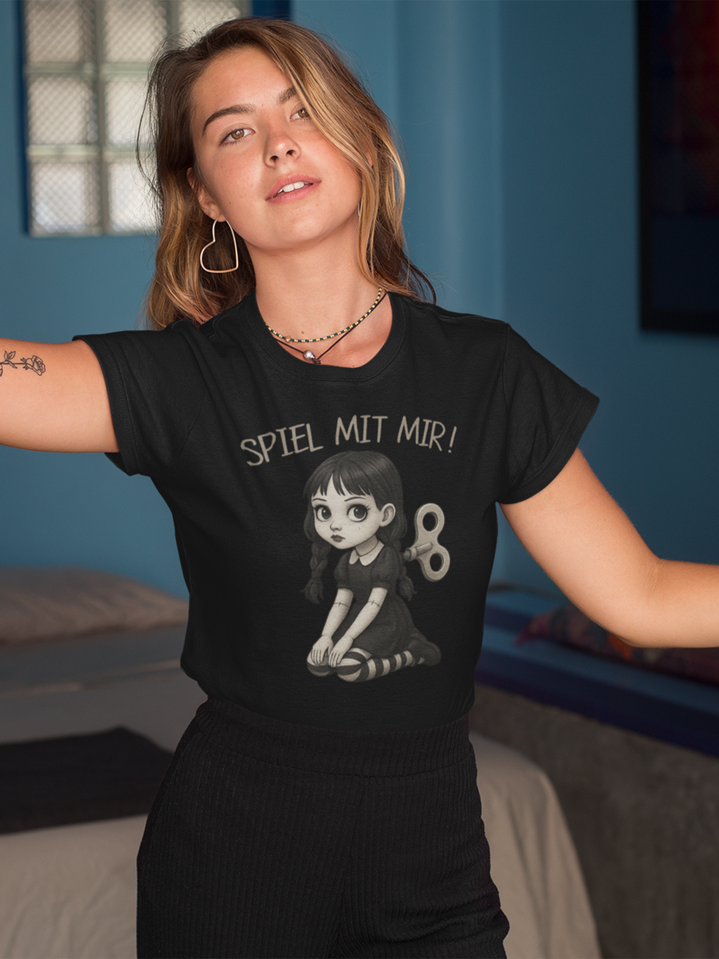 Blone junge Frau mit schwarzem T-Shirt mit Gothic Doll Motiv und Aufschrift "Spiel mit mir".