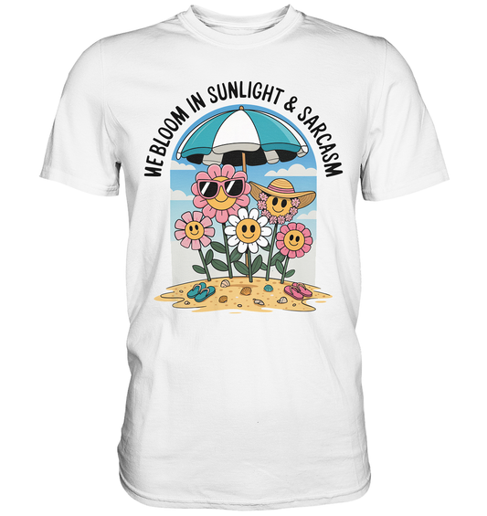 Weißes T-Shirt mit buntem Motiv: verrückte Blumen am Strand mit Sonnenbrillen und der Aufschrift „We bloom in sunlight and sarcasm"