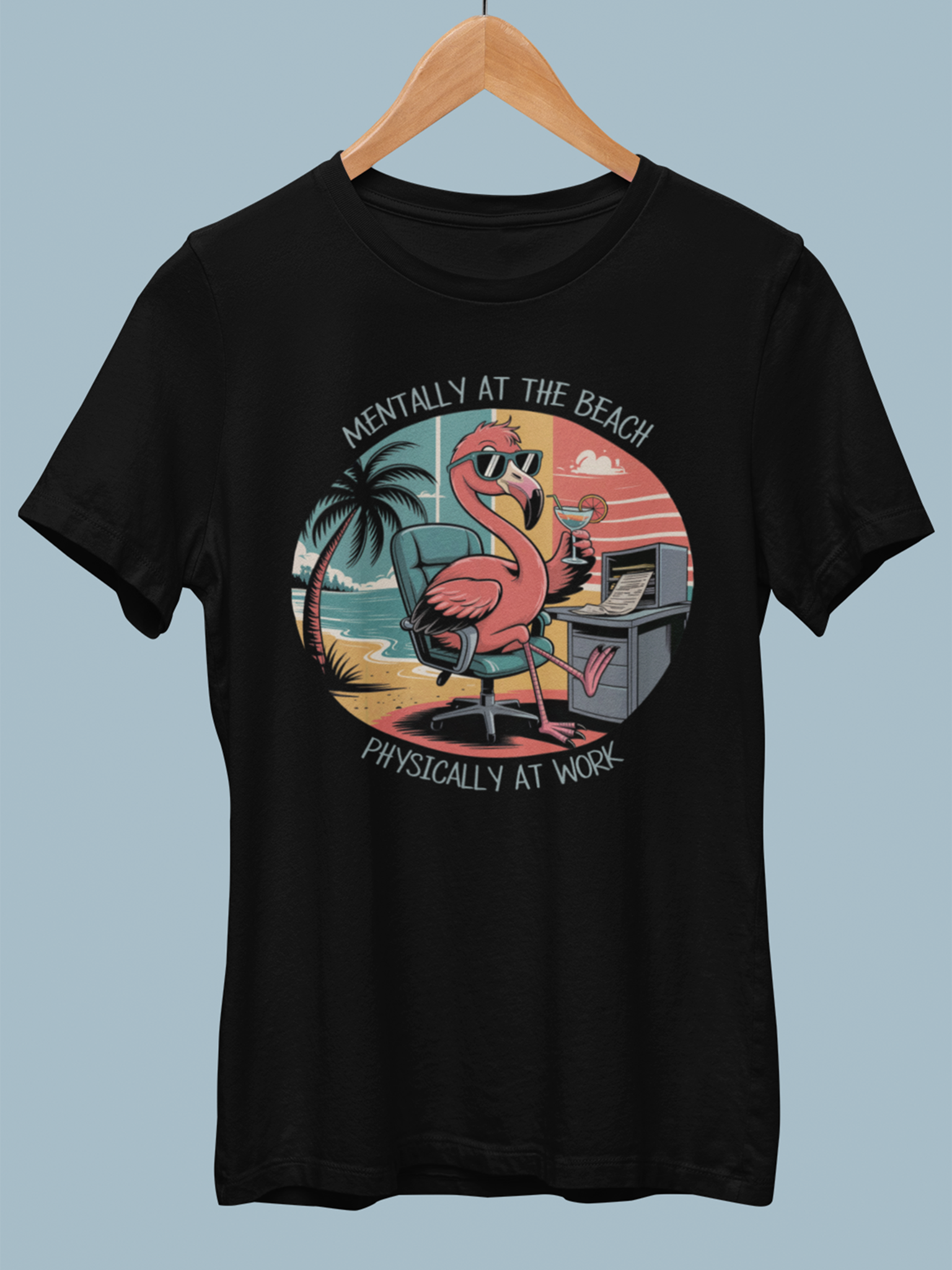 Schwarzes Shirt mit Flamingo-Motiv hängt auf Holzkleiderbügel.
