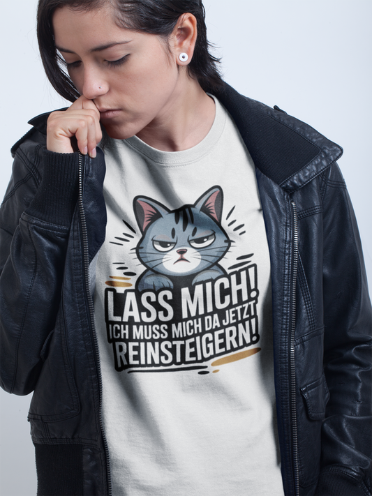 Junge Frau mit schwarzer Lederjacke. Darunter ein weißes Shirt mit großer Katze und Spruch "Lass mich! Ich muss mich da jetzt reinsteigern!"