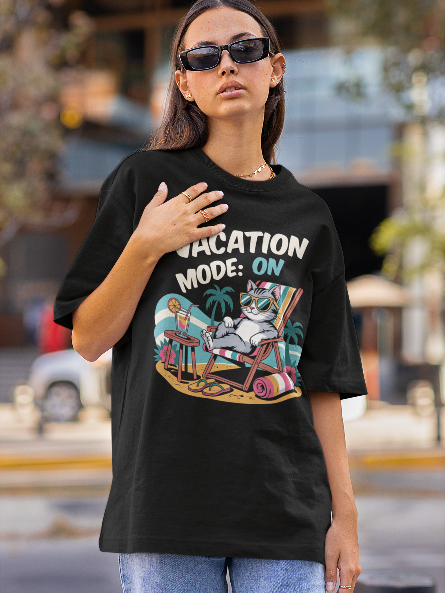 Junge Frau trägt ein schwarzes T-Shirt mit Comic-Motiv einer relaxenden Katze mit Sonnenbrille und dem Text „Vacation Mode On“